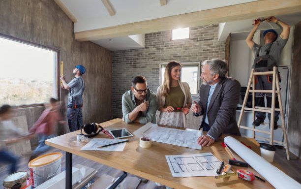 Happy parents talking about blueprints with interior designer during renovation of their home. Blurred motion.