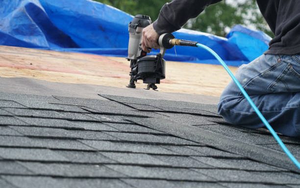 handyman using nail gun to install shingle to repair roof